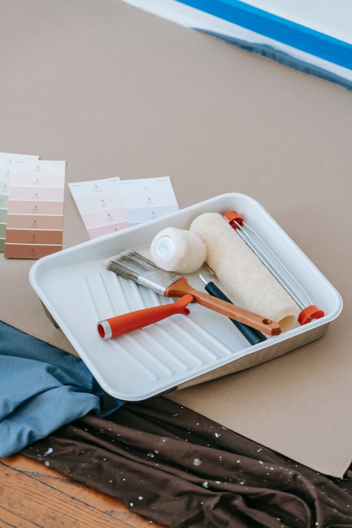 Paintbrush, roller, tray, and swatches for home renovation projects.
